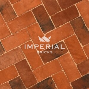 Tudor Multi handmade pavers laid in the ground. The brick pavers are orange and red with some darker shades blended in.