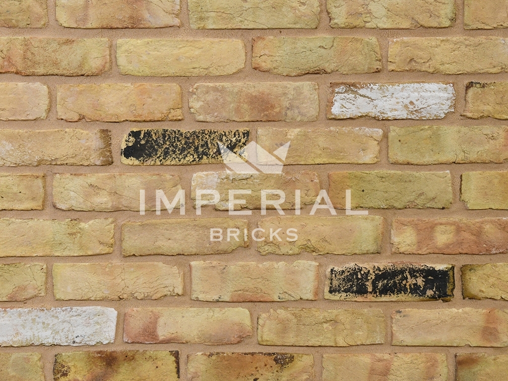 Yellow Stock bricks shown in a wall. The bricks have some darker overburns, with approximately 5% black and white faces.