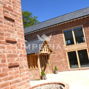 Large self-build residential home, built using Reclamation Cheshire handmade bricks. The bricks are shown close up in a wall on the left, with the entrance to the property on the right.