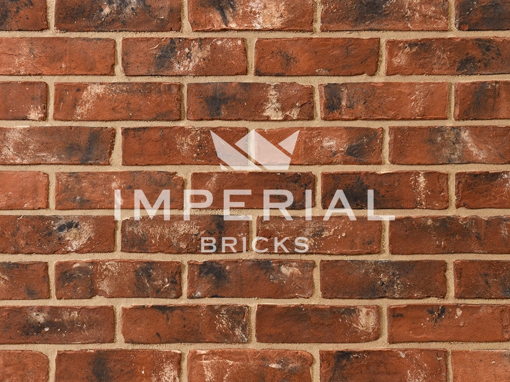 Reclamation Shire Blend bricks shown in a wall. The bricks are red and orange shades with traces of soot and lime mortar engrained in the faces.