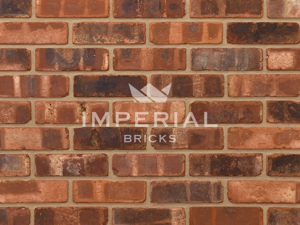 Tumbled Weathered Outside Blend bricks shown in a wall. The bricks have an orange/red base colour, pale banding, dark overburns, manufactured to replicate reclaimed bricks.