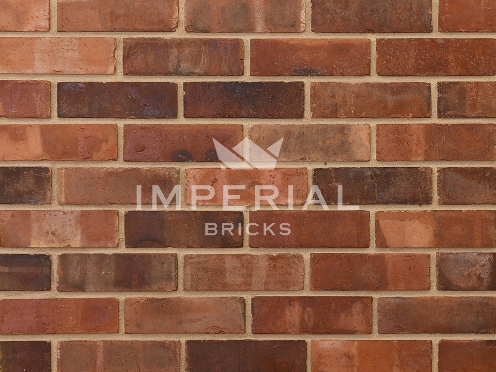 Weathered Pre War Common bricks shown in a wall. The bricks are red to orange colour, with pale banding, dark overburns and tonal weathering.