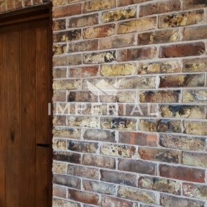 Wall next to an oak door built using York Clamp bricks with white lime mortar joints.