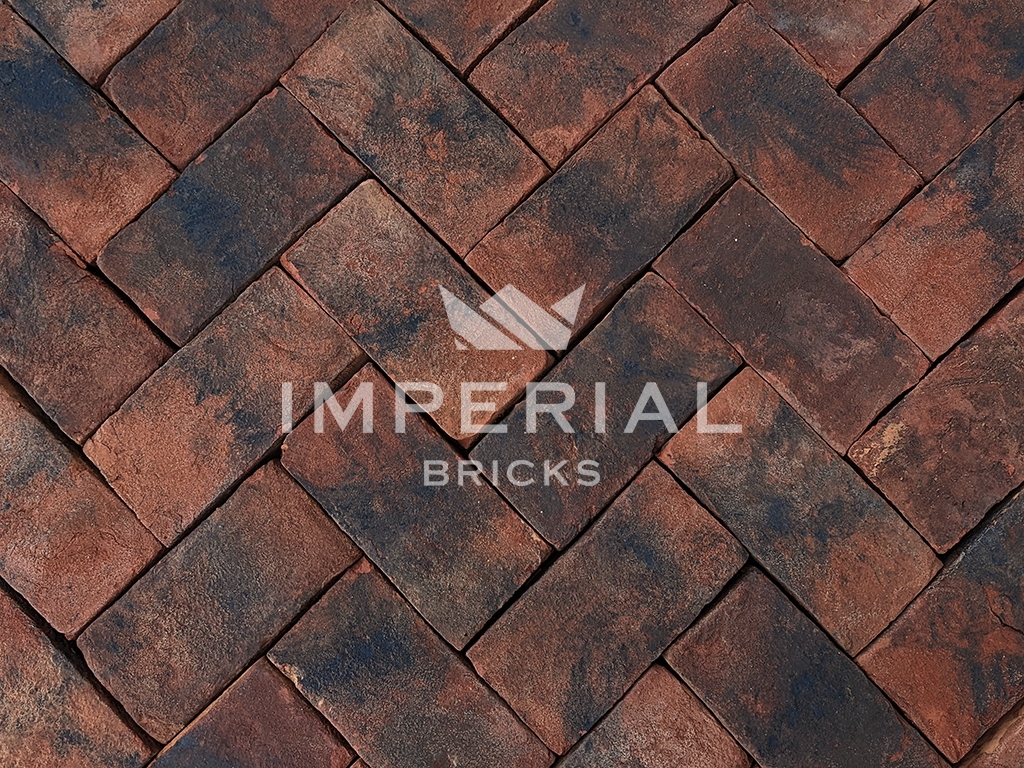 Balmoral Blend handmade pavers laid in the ground. The pavers are red with dark weathering and a sanded texture.