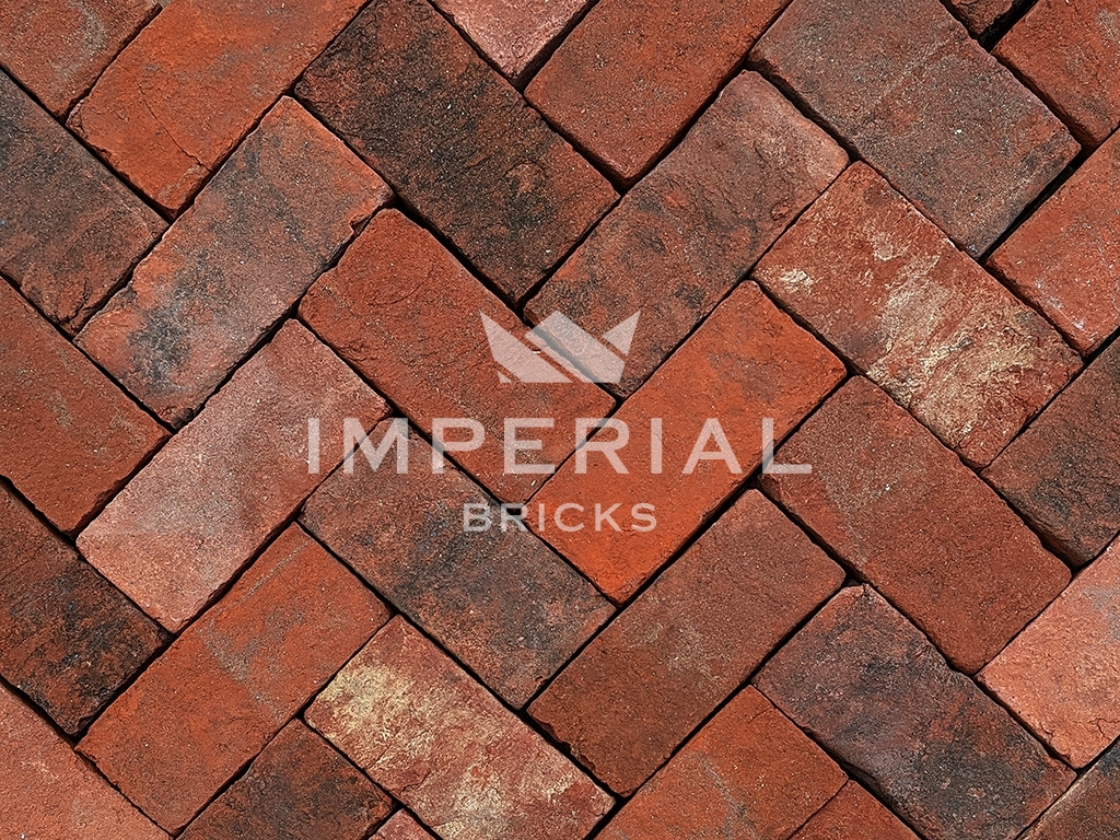 Sandringham Blend handmade pavers laid in a herringbone pattern. The pavers are blended red and orange colour shades with a weathered and aged finish.