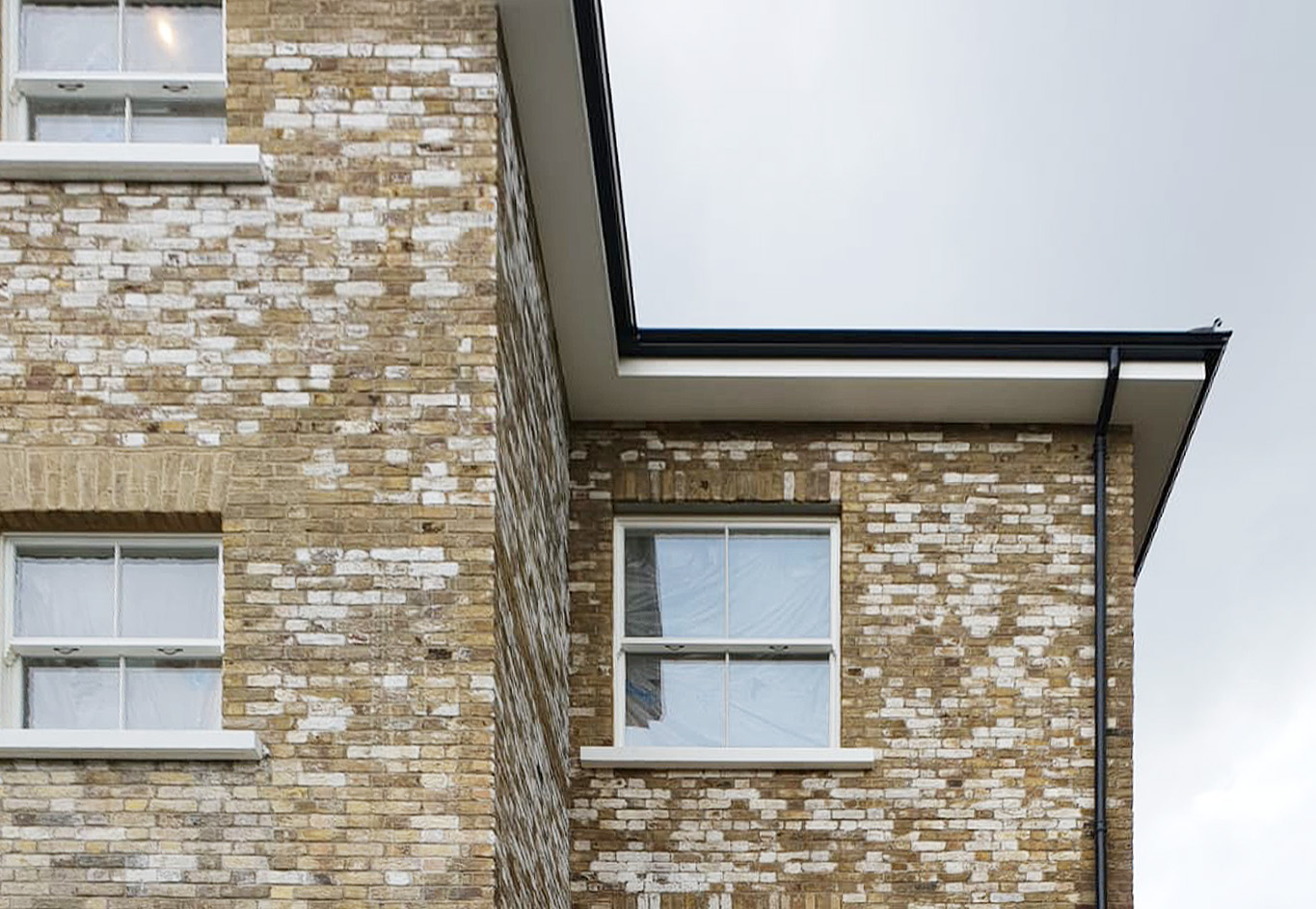 Second storey of a building with yellow brickwork. The brickwork has varying levels of efflorescence on the bricks. 