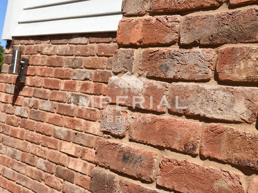 Corner of a wall built using red handmade tumbled bricks that replicate reclaimed bricks.