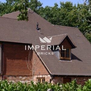 Dark Sandfaced machine made roof tiles shown on a large detached residential property.