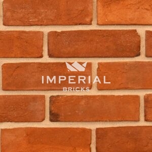 Heritage Soft Orange handmade bricks shown in a wall. The bricks have multi orange tones and creasing on the faces.