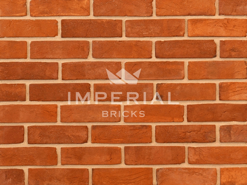 Heritage Soft Orange handmade bricks shown in a wall. The bricks have multi orange tones and creasing on the faces.