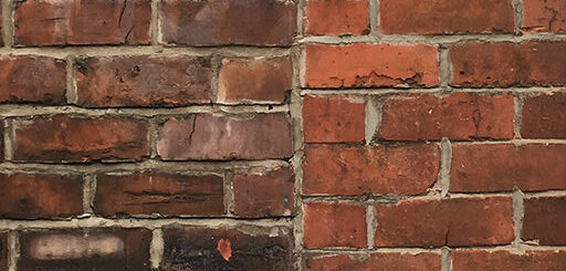 Brick wall which has been extended using the wrong size bricks, resulting in a mismatched join in the brickwork.