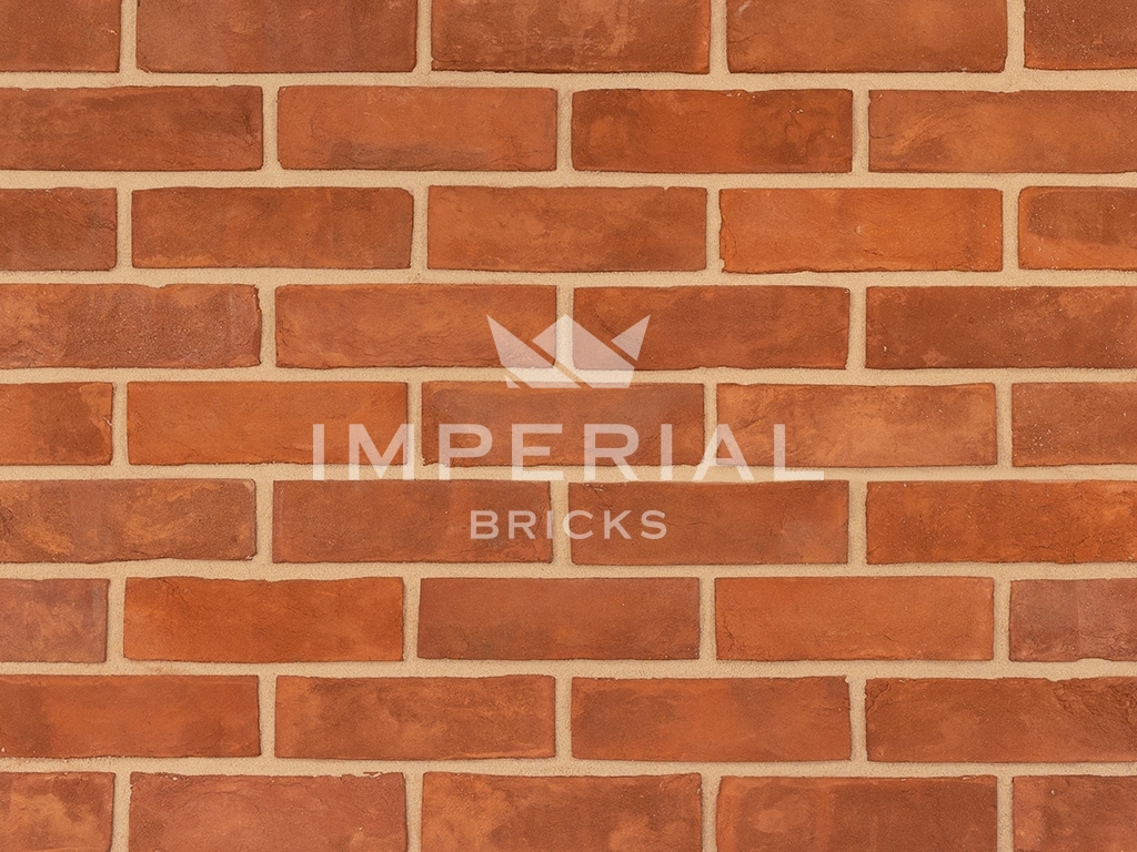 Soft Red bricks shown in a wall. The bricks have subtle colour variations and creasing on the faces.