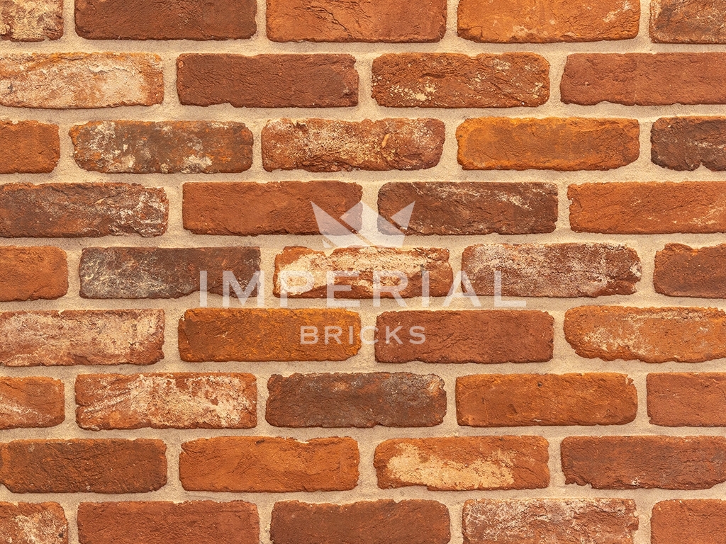Tumbled Regency Multi handmade bricks shown in a wall. The bricks are mixed orange and red Colours with soft edges and an aged reclaimed appearance.