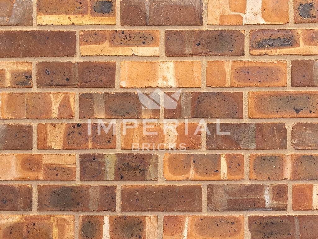 Weathered Cheshire Pre War bricks shown in a wall. The bricks are an orange base colour with tonal weathering and banding on the faces. Displayed with a mix of weathered and plain faces.