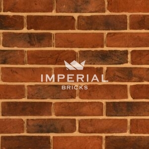 Urban Weathered Multi handmade bricks shown in a wall. The bricks feature a red shade with plain and weathered faces.