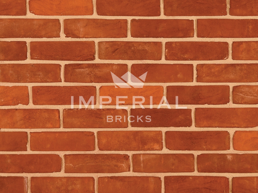 Regency Red Multi handmade bricks shown in a wall. The bricks are red blended with some oranges.