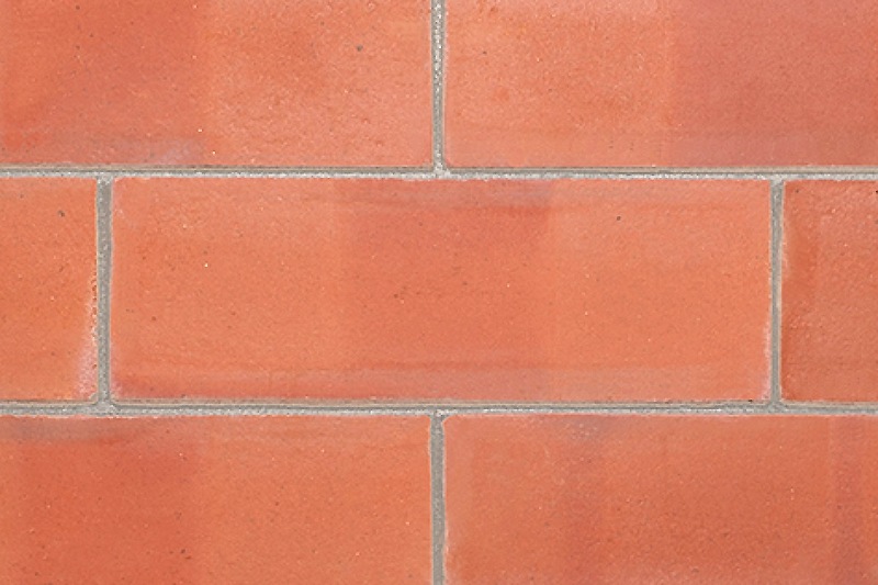 Pressed bricks in a wall, showing their smooth texture and straight, sharp edges which are typical characteristics of pressed bricks.