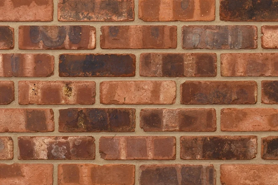 Example of pressed bricks with an aged finish shown in a wall. The bricks are aged by both weathered and tumbled finishes, creating soft, rounded edges and a characterful, rustic appearance.