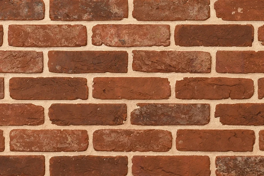 Example of red handmade bricks with a tumbled finish shown in a wall. The bricks have soft, rounded edges and a characterful, rustic appearance.