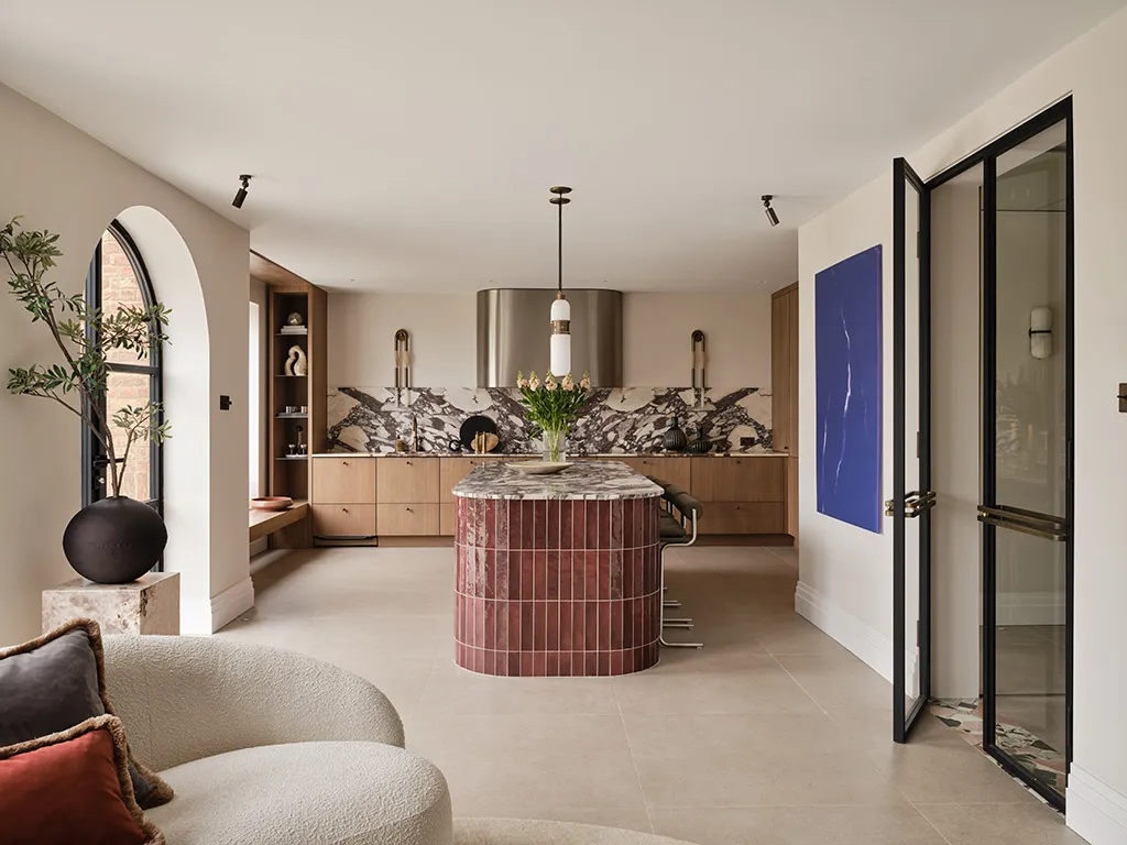 Wide kitchen view showing the full layout, including a central island finished with burgundy glossy linear tiles.