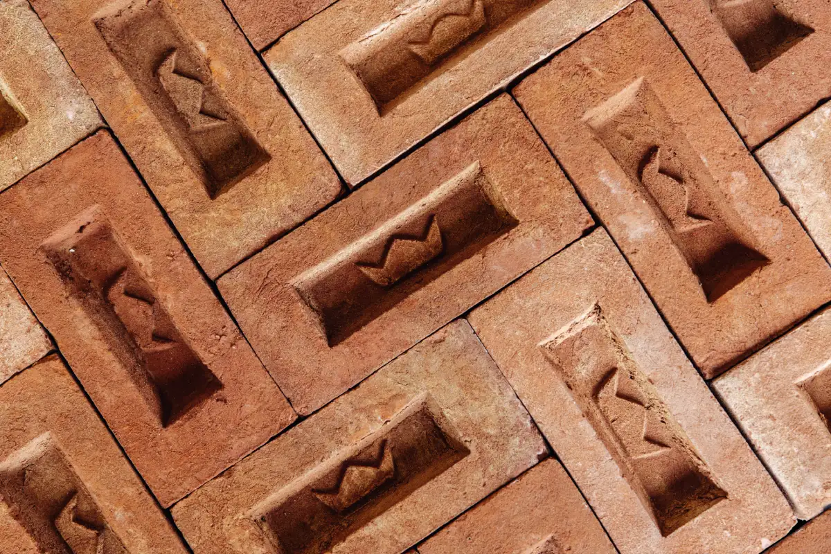 Red frogged bricks with the Imperial Bricks crown logo in the centre of the frog, laid out in a decorative herringbone pattern. The logo is an example of branded brick frogs.