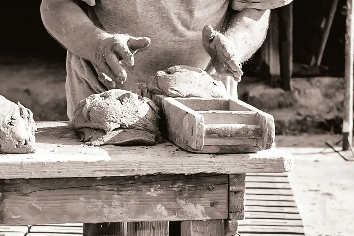 Example of traditional handmade brick production. A clot of clay is being thrown into a traditional wooden mould by hand.