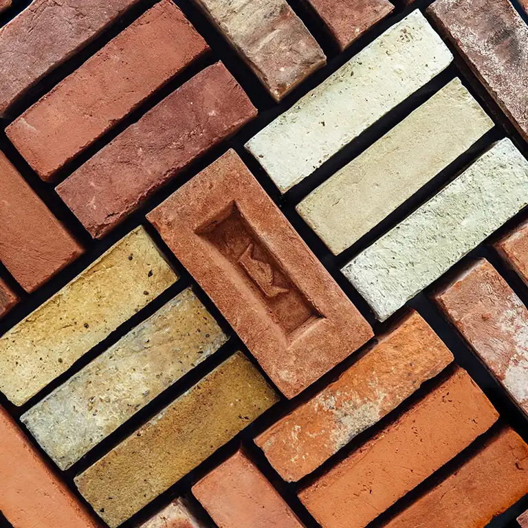 Imperial branded, frogged handmade brick in the centre, surrounded by handmade bricks in different colours.