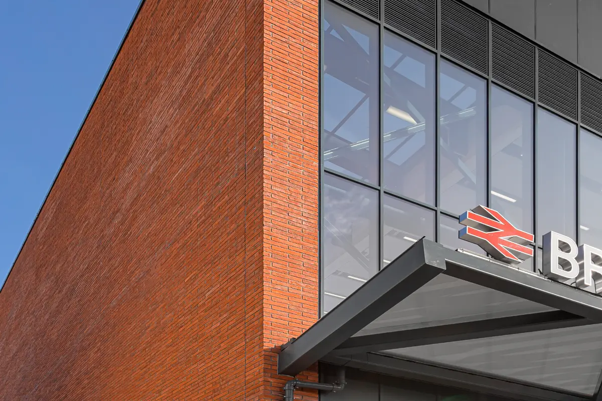 Exterior view of the Brent Cross West Station, featuring handmade linear brickwork alongside the glass window frontage.