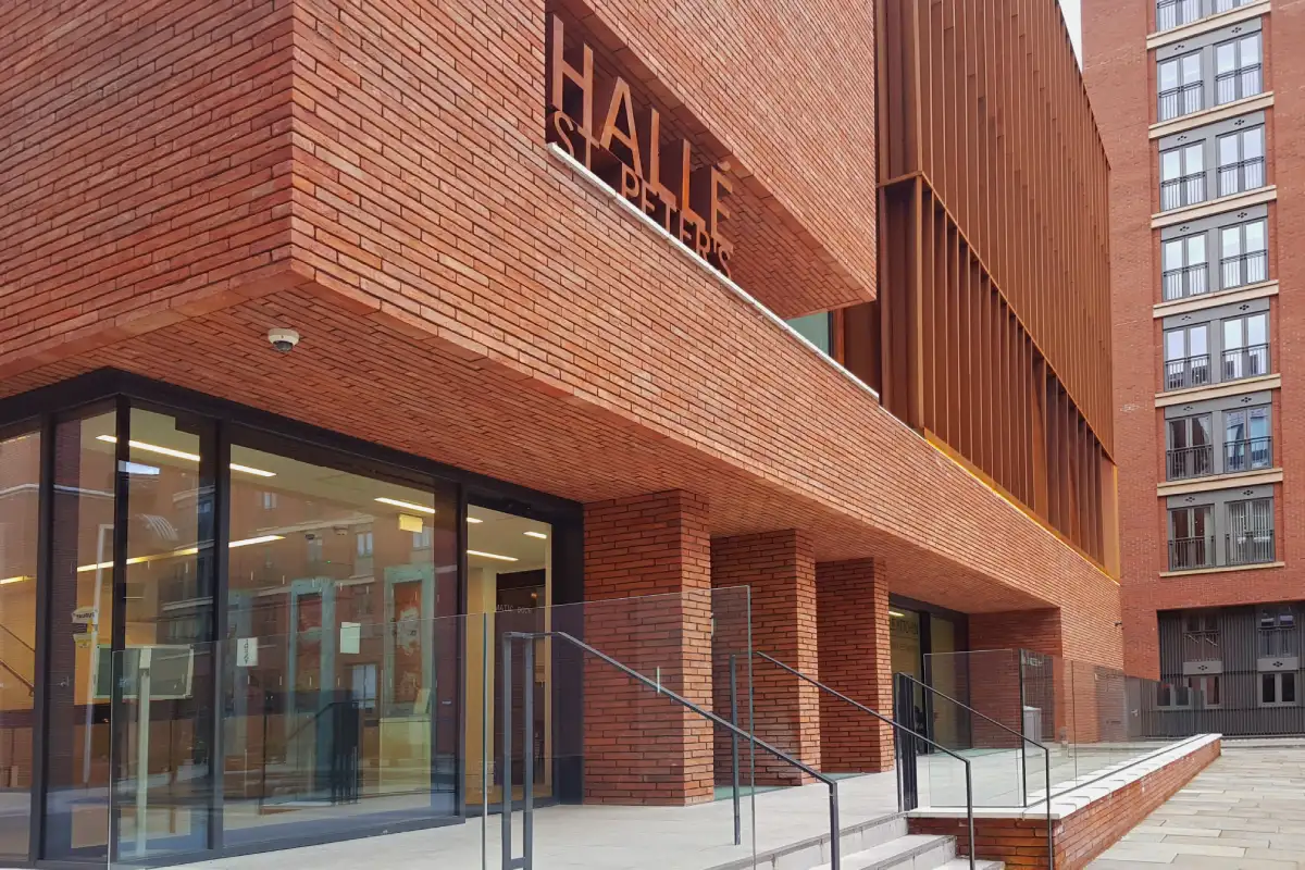 View of the main entrance to Halle St Peters in Manchester, showcasing the red multi handmade linear brickwork facade detailing and soffit.
